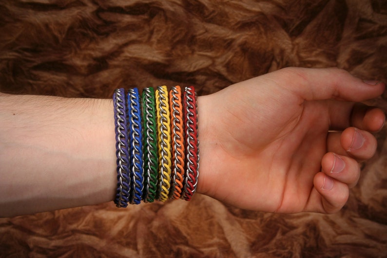 Pode incluir: Um conjunto de seis pulseiras de malha met&aacute;lica com elos prateados alternados com cord&otilde;es de cores vibrantes em roxo, azul, verde, amarelo, laranja e vermelho. Cada pulseira &eacute; constru&iacute;da com um padr&atilde;o repetitivo de segmentos met&aacute;licos.