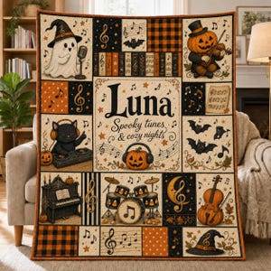 May include: A rectangular quilt featuring a Halloween theme with musical motifs. The center displays the text 'Luna Spooky tunes & cozy nights' surrounded by pumpkins, a ghost, a cat with headphones, a piano, drums, and a cello, all in orange, black, and cream.