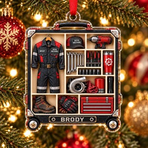 May include: A rectangular Christmas ornament shaped like a tool case, featuring a black and red jumpsuit with the name BRODY, a DIESEL MECHANIC cap, a red power drill, wrenches, a red tumbler, a turbocharger, boots, gloves, and a red toolbox.
