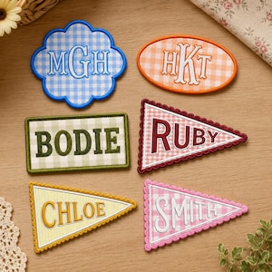 May include: Six embroidered fabric patches with gingham patterns and personalized text. Includes a blue cloud shape with MGH, an orange oval with HKT, a green rectangle with BODIE, and three triangular pennants with RUBY, CHLOE, and SMITH.