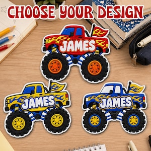 May include: Three embroidered monster truck patches featuring the name JAMES in white bubble letters. One patch is red with yellow flames, one is yellow with blue flames, and one is blue with yellow flames, each with a small flag on the back.