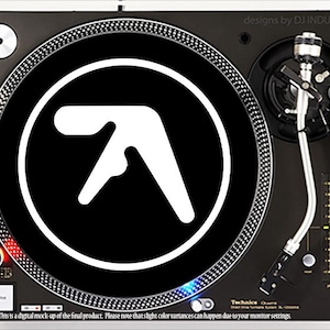 May include: A black turntable with a white logo of the letter 'A' in a circle on the platter. The turntable is a Technics SL-1200 MK2. The text 'designs by DJ INDUSTRIES' is in the upper right corner of the image.