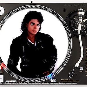 May include: A black and white image of a DJ turntable with a custom vinyl record featuring a portrait of Michael Jackson. The record is white with a black border and a black and white image of Michael Jackson in a black leather jacket. The turntable is black with silver accents and a silver tone arm. The text "designs by DJ INDUSTRIES" is visible in the upper right corner of the image.