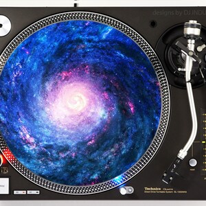 May include: A black turntable with a galaxy-themed slipmat. The slipmat features a swirling blue and pink galaxy with stars. The turntable has a silver tone tonearm and a black platter.