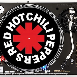 May include: A black and silver turntable with the words "RED HOT CHILI PEPPERS" in white around a red asterisk on the record. The turntable has a silver tone arm and a black base. The text "designs by DJ INDUSTRIES" is visible.