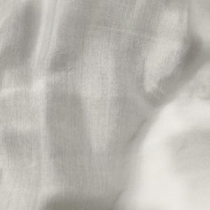 Peut inclure: Gros plan sur un tissu blanc à la texture subtile. Le tissu semble léger et légèrement translucide, avec des fils tissés visibles. Les plis et les ombres créent de la profondeur et un intérêt visuel.