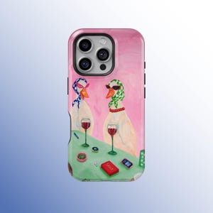 May include: A pink phone case featuring a painting of two geese wearing sunglasses and headscarves, holding wine glasses. The geese are at a table with a green tablecloth, a red box labeled "Sassy", and other items.