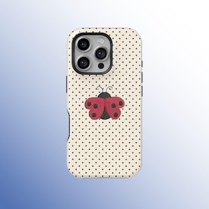 May include: A phone case with a cream-colored background covered in small black polka dots. A red and black ladybug design is centered on the case. The case has a black border around the camera lenses.