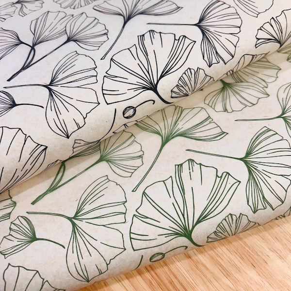 Könnte beinhalten: Off-white Papier mit einem sich wiederholenden Muster aus Ginkgoblättern. Die Blätter sind in Schwarz und Grün umrandet und bilden ein botanisches Design. Das Papier ist gefaltet und zeigt die Kontinuität des Musters.