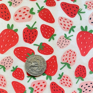 May include: A fabric with a repeating pattern of red and pink strawberries with green stems on a white background. A quarter coin is included for scale.
