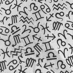 Può includere: Primo piano di un tessuto grigio chiaro ricoperto di simboli zodiacali neri. I simboli sono sparsi sulla superficie, creando un motivo ripetuto. I simboli includono Ariete, Toro, Gemelli, Cancro, Leone, Vergine, Bilancia, Scorpione, Sagittario, Capricorno, Acquario e Pesci.