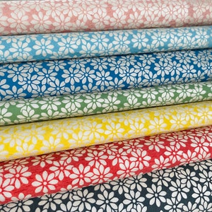 Pode incluir: Um rolo de tecido com um padrão floral branco sobre um fundo rosa, azul, verde, amarelo, vermelho e preto.