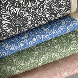 May include: Four pieces of fabric with a lace pattern. The top layer is black, the second layer is blue, the third layer is green, and the bottom layer is pink.