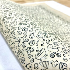 Puede incluir: Una hoja de papel de regalo blanco con un patrón en blanco y negro de iconos relacionados con bebés. Los iconos incluyen un biberon, un sonajero, un chupete, un cochecito, un osito de peluche, una bañera, un tren de juguete, una pelota, un par de zapatos, un babero, una cuchara, un tenedor, un pañal, un monitor de bebé, una cuna, un caballo de balancín, un móvil, una estrella, un corazón y una luna creciente.