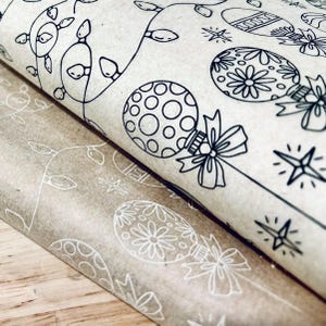May include: Two sheets of brown wrapping paper with a black and white Christmas design. The design features ornaments, stars, and lights.