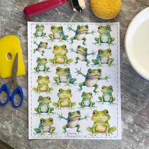 May include: A sheet of paper with multiple watercolor illustrations of green frogs in various poses. The frogs have yellow eyes and are set against a white background. The text "Tree Frogs" and "elandecals.com" is visible at the bottom.