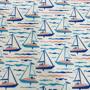 May include: A white background with a repeating pattern of blue and pink sailboats on blue and pink waves. The sailboats are all facing the same direction and have a simple design.