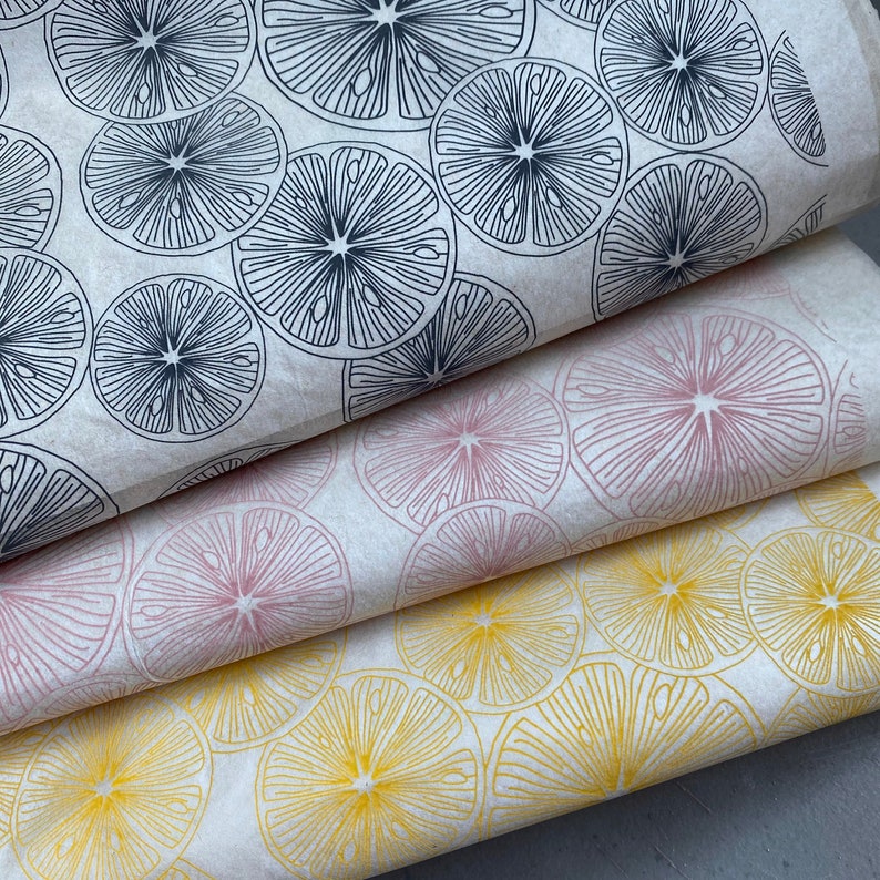 Pode incluir: Tr&ecirc;s folhas de papel de embrulho com um padr&atilde;o de fatias de lim&atilde;o. A folha superior tem fatias de lim&atilde;o pretas sobre um fundo branco. A folha do meio tem fatias de lim&atilde;o cor-de-rosa sobre um fundo branco. A folha inferior tem fatias de lim&atilde;o amarelas sobre um fundo branco.