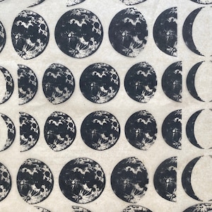 May include: A white background with a repeating pattern of black moons in various phases. The moons are arranged in rows and columns, with each row showing a different phase of the moon.