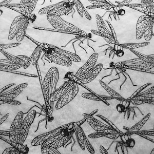 May include: Black and white patterned fabric with a repeating design of dragonflies. The dragonflies are detailed with intricate wing patterns.