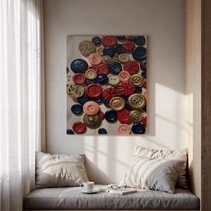 Puede incluir: Una obra de arte enmarcada que presenta una colección de botones en tonos rojo, azul marino, melocotón y dorado. Los botones son de diferentes tamaños y diseños, creando una composición texturizada. La obra se exhibe en un rincón de lectura.