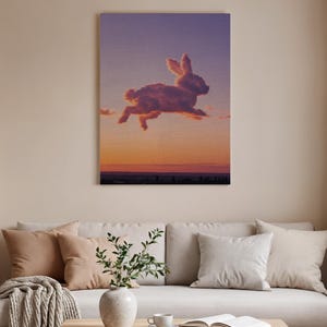 May include: A canvas print depicts a rabbit-shaped cloud leaping across a sunset sky. The artwork features a gradient of colors, from purple to orange, with the silhouette of a cityscape at the bottom. The rabbit is a light brown color.