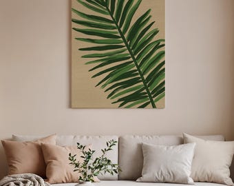 May include: A rectangular canvas art piece featuring a large, stylized green palm leaf against a beige background. The artwork is mounted on a wall above a beige sofa with decorative pillows and a vase with greenery.