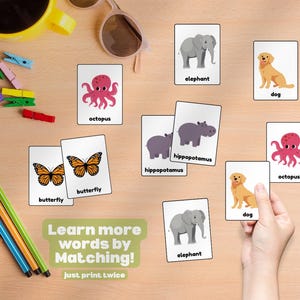 May include: Flashcards featuring animal illustrations, such as an elephant, dog, and octopus, displayed on a wooden surface. The cards are accompanied by the text "Learn more words by Matching!" and "just print twice".