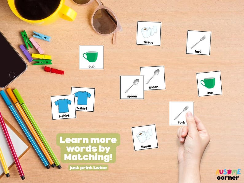 May include: Educational matching game with illustrated cards featuring a green cup, blue t-shirts, spoons, forks, and tissue. The text "Learn more words by Matching!" is visible. Other items include pens, a phone, and sunglasses.
