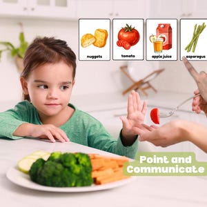 May include: A child in a green top is shown with a plate of vegetables. The child is refusing a tomato slice offered on a fork. The image includes cards with pictures of nuggets, tomato, apple juice, and asparagus. Text reads "Point and Communicate".