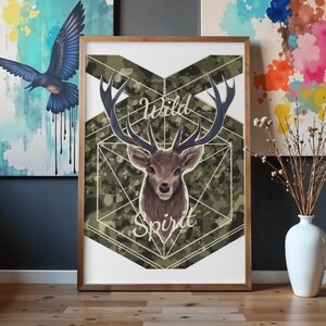 Può includere: Stampa artistica incorniciata raffigurante un cervo con grandi corna, su uno sfondo mimetico. Le parole "Wild Spirit" sono scritte in corsivo. L'opera è in una cornice di legno, con altre opere d'arte sullo sfondo.
