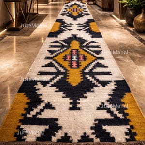 May include: A long runner rug featuring a repeating geometric pattern in black, white, and mustard yellow. The design includes central diamond shapes with pink and white accents. The text JuteMahal is visible in multiple locations on the rug.