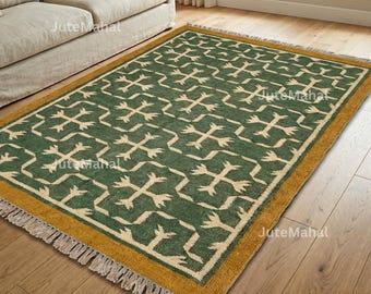 May include: A rectangular green and beige patterned rug with a gold border and fringe. The rug features a repeating geometric design. The rug is placed on a wooden floor next to a beige sofa.