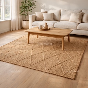 May include: A rectangular, natural-toned jute rug with a diamond pattern. The rug is placed on a light-colored wooden floor, beneath a wooden coffee table and a white sofa with beige cushions. The room is well-lit with natural light.