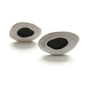 May include: A pair of silver earrings with a black oval shape in the center of each earring.