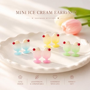 May include: Miniature ice cream earrings featuring small sundae cups in pastel blue, yellow, pink, and green. Each earring has a textured cream scoop topped with a tiny red cherry. The text MINI ICE CREAM EARRINGS is displayed at the top.