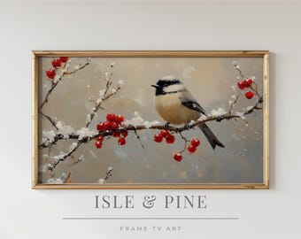 May include: A framed painting of a bird perched on a snow-covered branch with red berries. The artwork has a gold frame and the text "ISLE & PINE" and "FRAME TV ART" at the bottom. The bird has a black and white head and a tan body.