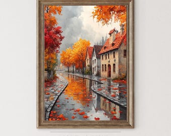 May include: A framed art print of a European village scene in autumn. The artwork features a cobblestone street reflecting the orange and red foliage of the trees. The buildings have red tile roofs. The text "ISLE & PINE" is at the bottom.