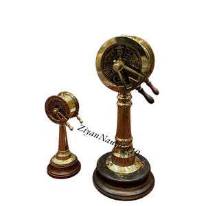 May include: Two brass ship's telegraphs, one large and one small, with wooden handles and bases. The telegraphs have dials with text indicating speed commands like "Full", "Half", and "Stop". The larger one is on a dark base.