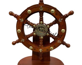 May include: A dark brown wooden ship's wheel with brass studs and anchor motifs. The wheel is mounted on a matching wooden base. The image includes the text "Liyan Nautical 10".