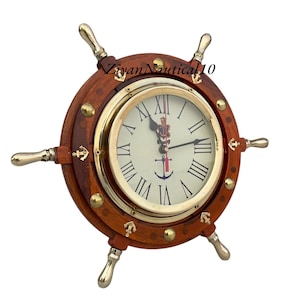 Op de afbeelding: Een nautische klok in de vorm van een scheepsstuurwiel. De klok heeft een houten frame met messing accenten en een crèmekleurige wijzerplaat met Romeinse cijfers. De tekst "Ziyan Nautical 10" is zichtbaar.