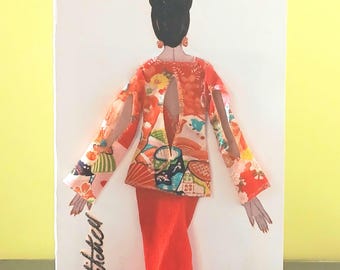 May include: A vertical rectangular card featuring a collage of a figure seen from the back. The figure wears a bright orange long skirt and a patterned orange top with cut-out sleeves and a back opening. The text "Willie Stitched" is written in black.