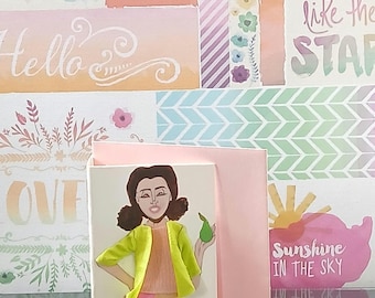 May include: A greeting card featuring a hand-drawn illustration of a person with dark hair wearing a lime green jacket, a peach top, a multi-colored patchwork skirt, and yellow leggings, holding a green pear. The card is set against a pink background.