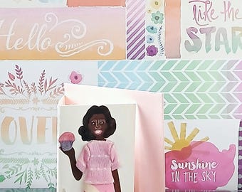 May include: A greeting card featuring a three-dimensional paper cutout of a person with dark hair, wearing a pink textured short-sleeved top, a pink and white skirt, and patterned leggings, holding a small pink cupcake in one hand.