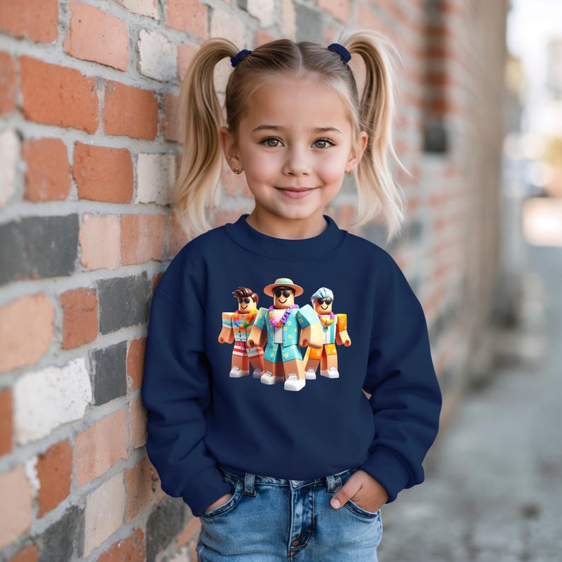 Puede incluir: Una sudadera azul marino con un gr&aacute;fico de tres personajes de Roblox con ropa de vacaciones. Los personajes llevan gafas de sol, sombreros y camisas hawaianas. La sudadera la lleva una ni&ntilde;a peque&ntilde;a con coletas rubias.