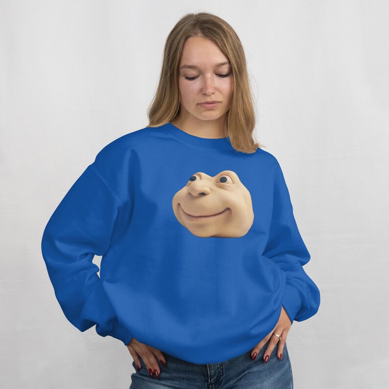 May include: A royal blue sweatshirt with a large, smiling cartoon face. The face is a light beige colour with dark eyes and a curved mouth. The sweatshirt is a solid colour and has a crew neck.