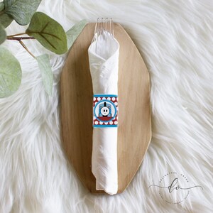 Könnte beinhalten: Eine weiße Serviette mit einem blauen und roten Thomas-der-Tankmotor-Serviettenring. Der Serviettenring hat weiße Punkte auf rotem Hintergrund und zeigt ein Cartoon-Bild von Thomas der Tankmotor.