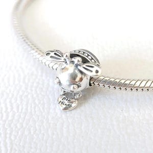 Könnte beinhalten: Ein silberner Charm-Anhänger in Form einer Biene mit schwarzen Akzenten auf Flügeln und Kopf. Befestigt an einem silbernen Armband. Ein kleines Herz darunter trägt die Aufschrift "Bee Mine".