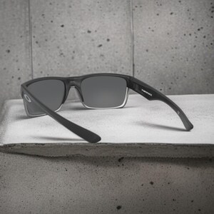 May include: Black sunglasses with gray lenses and the text "TWINFACE" on the temple. The sunglasses have a rectangular frame and are set against a gray background.