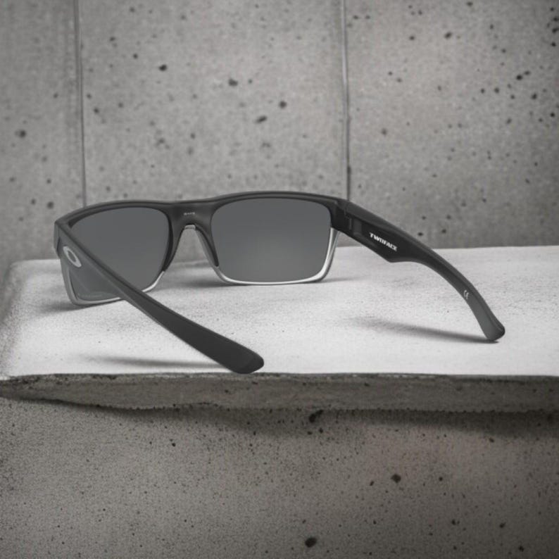 May include: Black sunglasses with gray lenses and the text "TWINFACE" on the temple. The sunglasses have a rectangular frame and are set against a gray background.